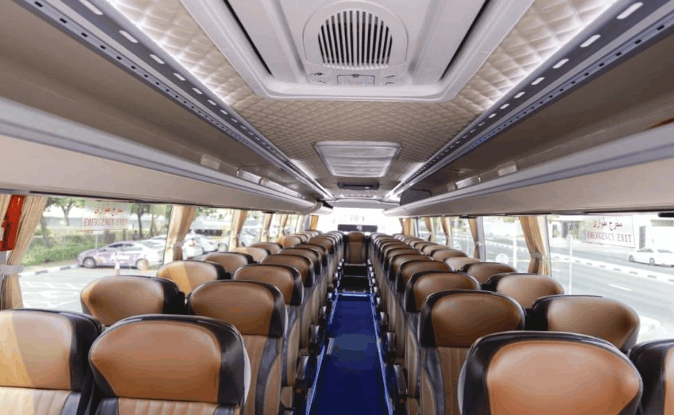 Inside a King Long coach: rows of tan leather seats either side of a central aisle, curtained windows, air-conditioning along the ceiling