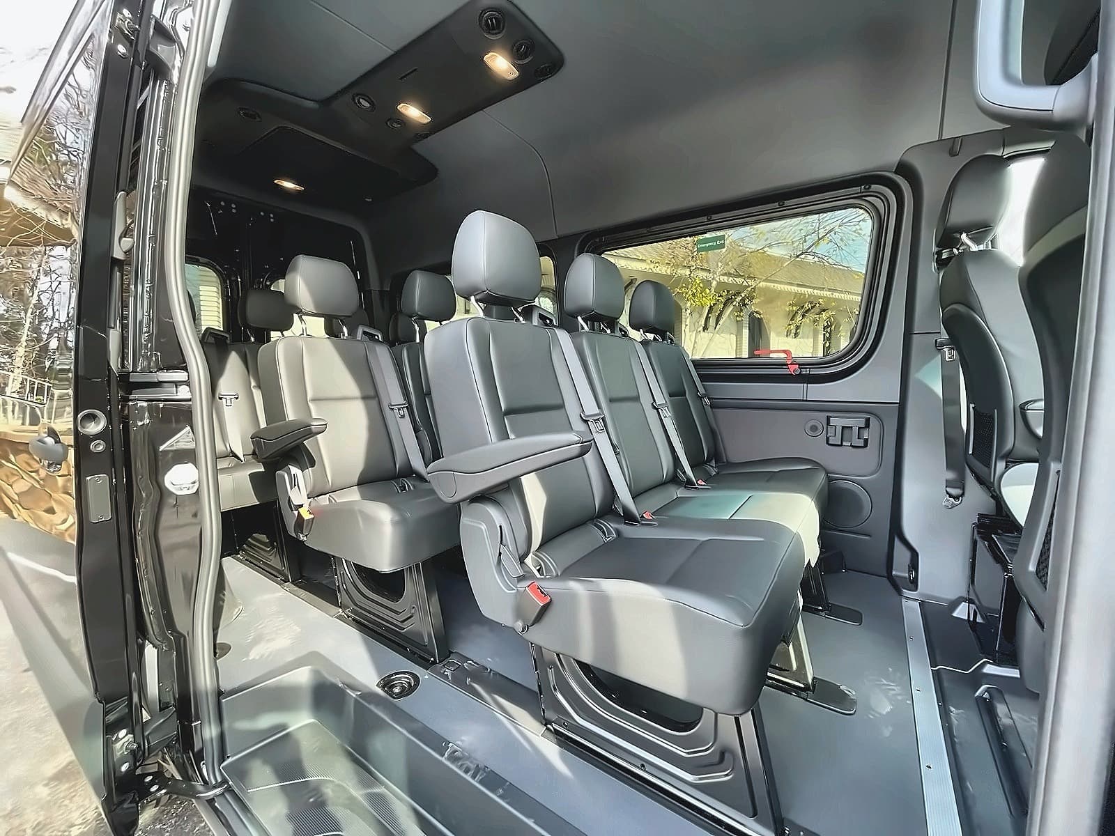 Inside TFSL's Mercedes Sprinter with every row of grey seats fitted, seen through the open side door